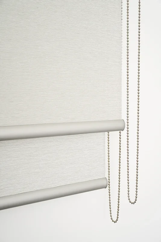 Detail of a double roller blind: two rolls on one bracket set, front and back base rails at different heights, two bead-chain loops