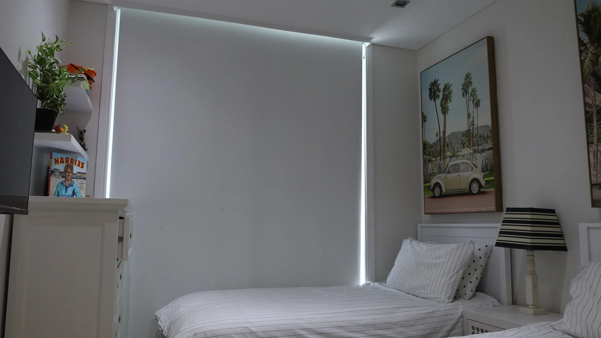 A white blockout roller blind fully lowered in a kids bedroom, with a thin line of light at the edges