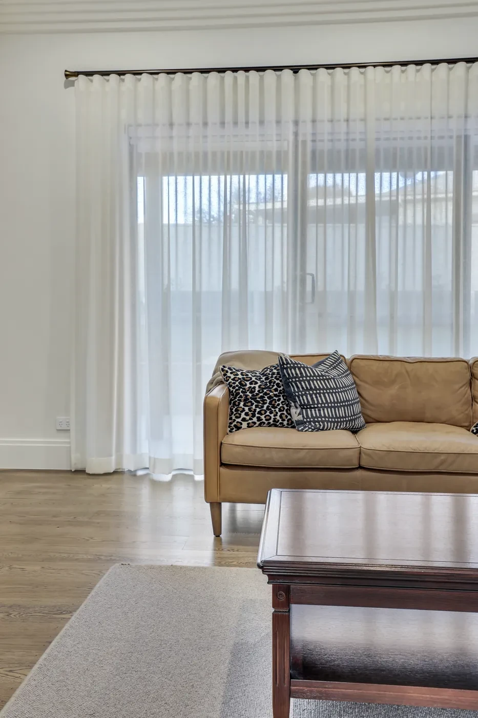 Tan sofa in front of sheer curtains Tan sofa in front of sheer curtains