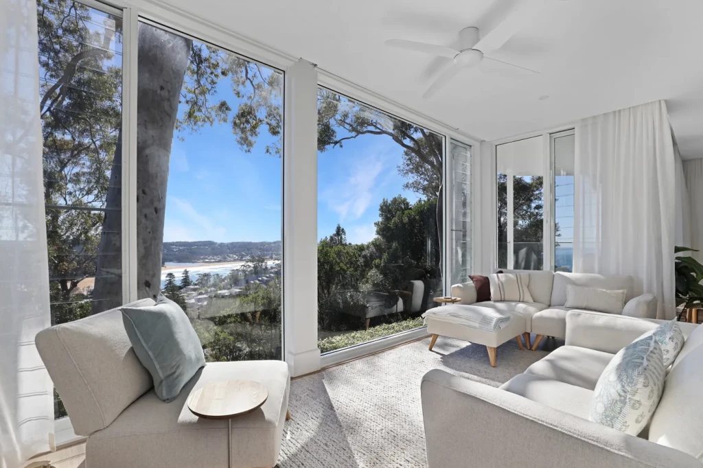 Sheer curtains drawn back from full-height glass with a beach view Sheer curtains drawn back from full-height glass with a beach view