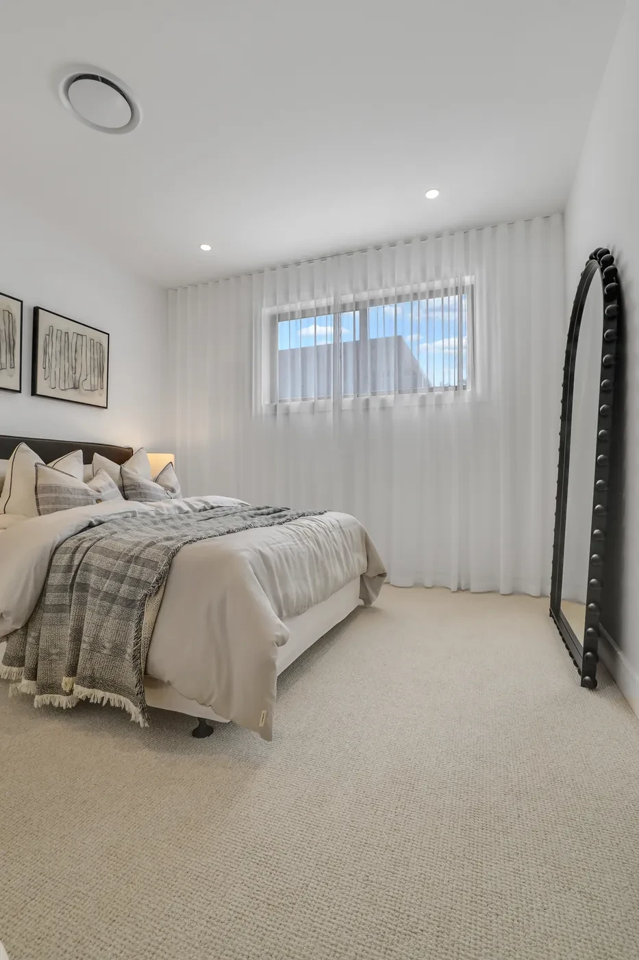 Bedroom with sheer curtains and an arched mirror Bedroom with sheer curtains and an arched mirror