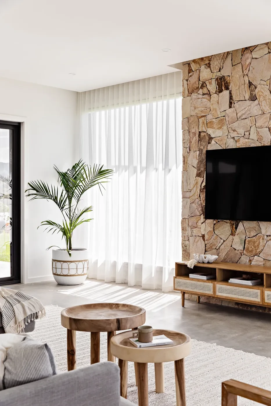 Living room with a stone feature wall and sheer curtains Living room with a stone feature wall and sheer curtains