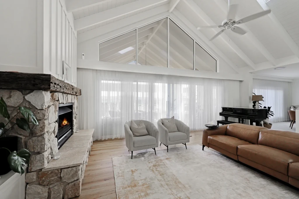Sheer curtains along a vaulted living room with a stone fireplace, Abercrombie Residence