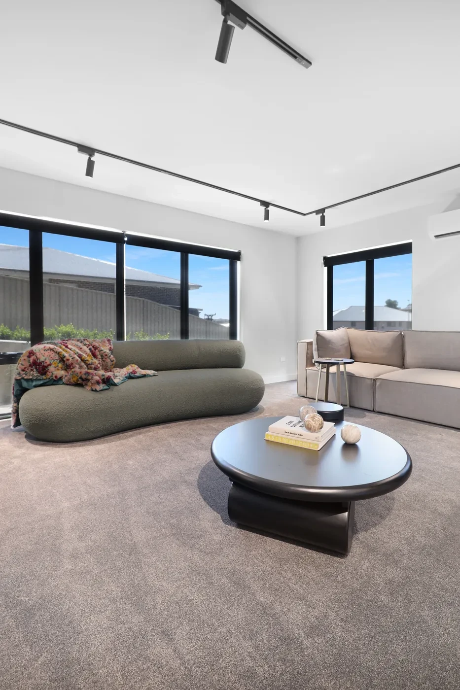 Charcoal sunscreen roller blinds half-lowered across a living room window wall Charcoal sunscreen roller blinds half-lowered across a living room window wall