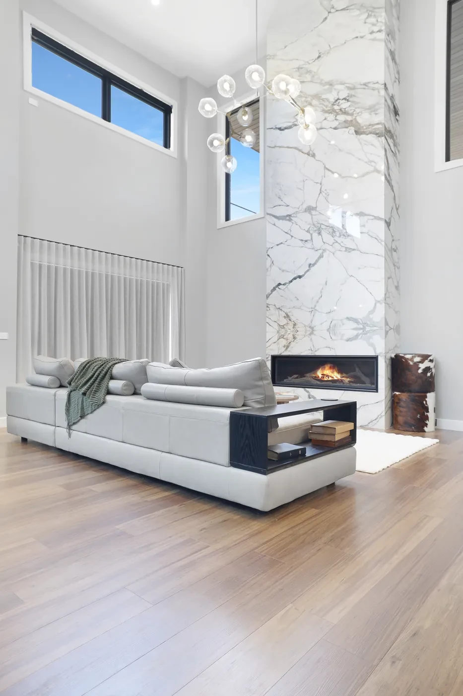 Double-height living room with sheer curtains and a marble fireplace Double-height living room with sheer curtains and a marble fireplace