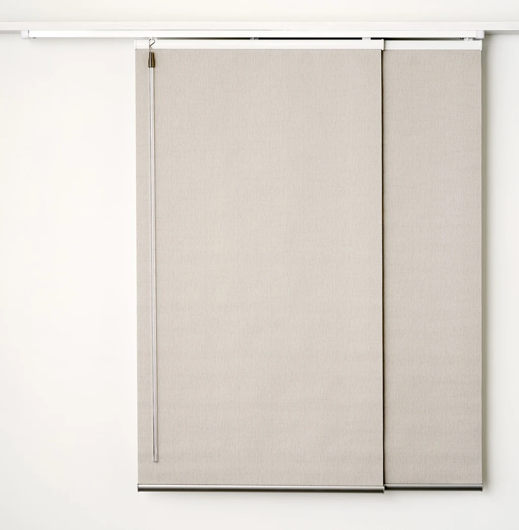 Two beige panel glide blinds hanging from a white track (supplier studio photo)