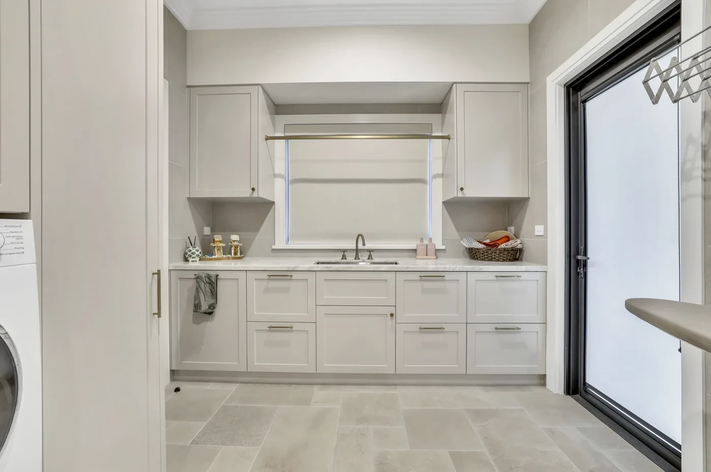 White roller blind lowered over a laundry window White roller blind lowered over a laundry window