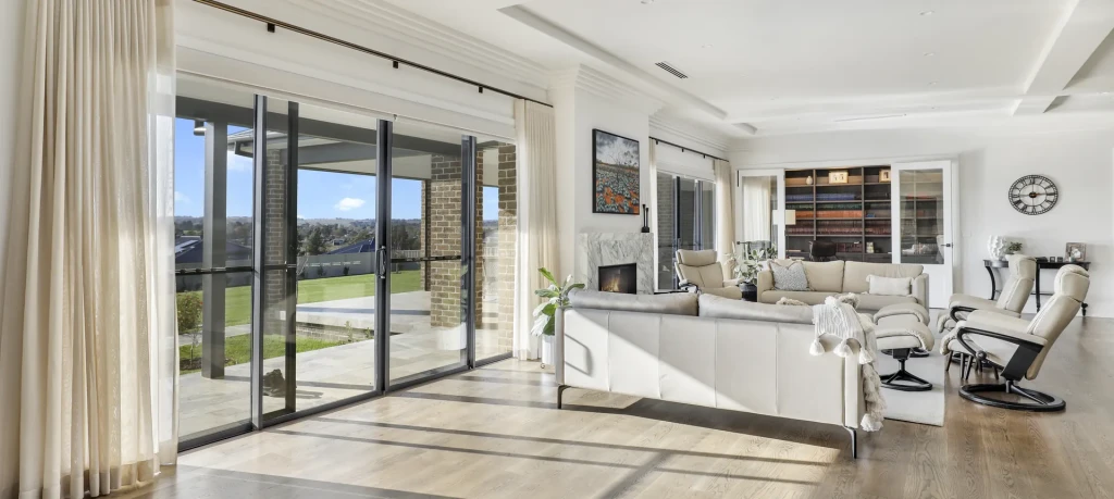 Sheer curtains across a sunlit living room opening, fitted by the owners