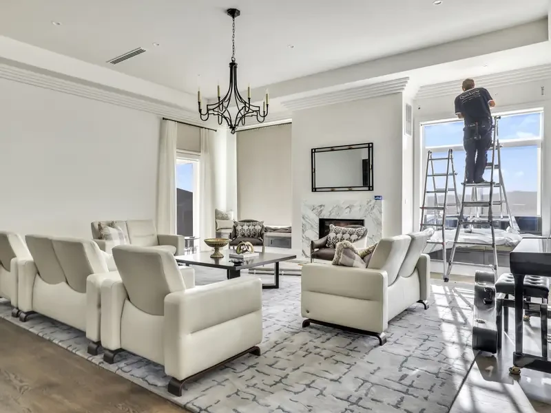 A man on a step ladder at a tall lounge room window