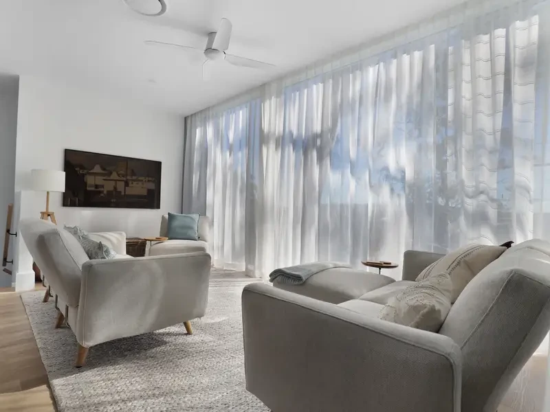 White sheer curtains in S-Fold waves across a lounge room window wall