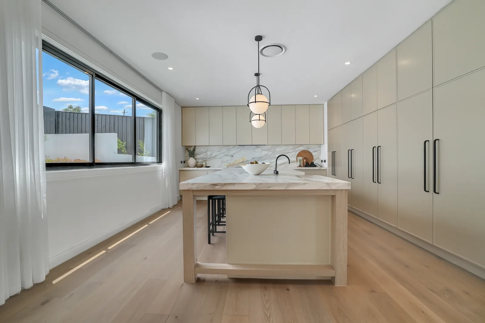 Kitchen with white S-Fold sheer curtains along the window wall