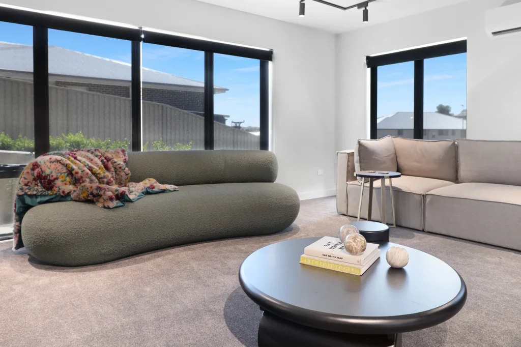 Charcoal sunscreen roller blinds raised to the head of a lounge room window wall