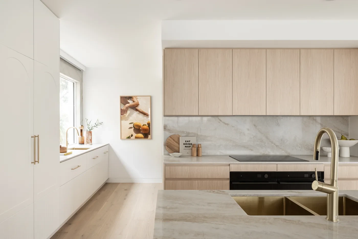 A greige sunscreen roller blind part-lowered over a kitchen window above the benchtop