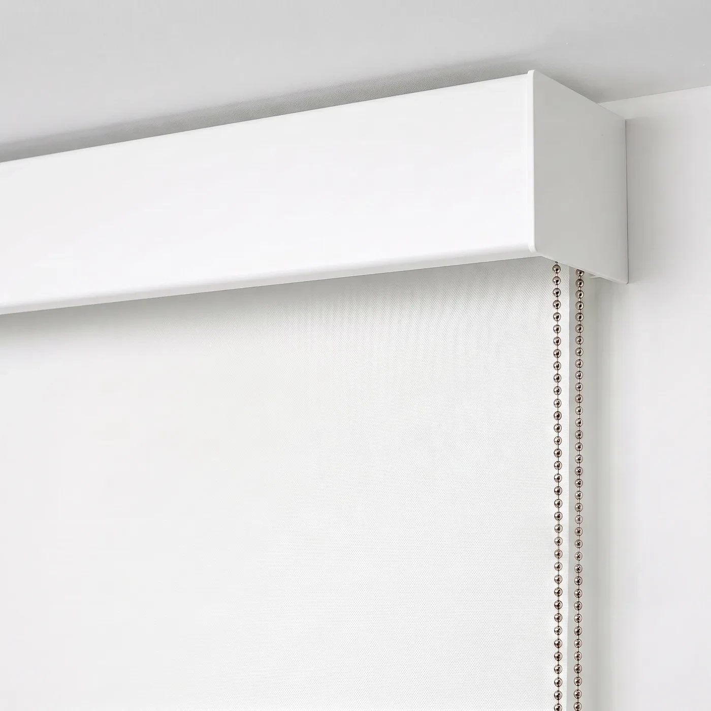 Close-up of a white square metal pelmet over the top of a white roller blind
