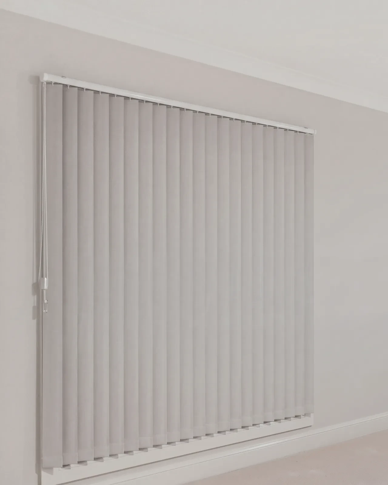 A grey fabric vertical blind face fitted over a bedroom window, flat vanes closed A grey fabric vertical blind face fitted over a bedroom window, flat vanes closed