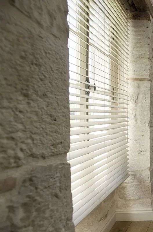 White Purewood timber venetian blind fitted inside a deep window reveal, slats part-open