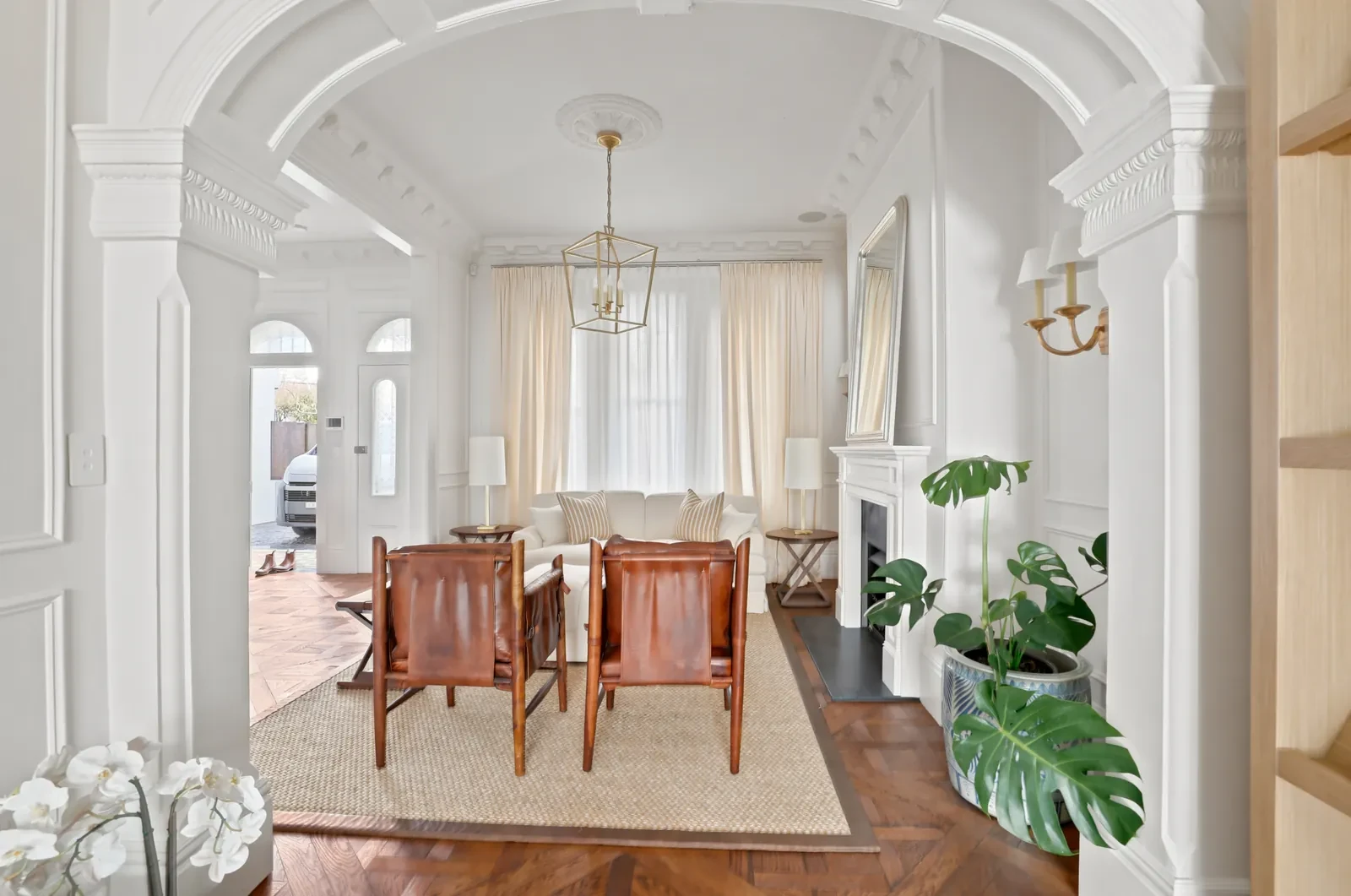 Front formal room seen through an arched doorway, with layered sheers and curtains on the tall windows