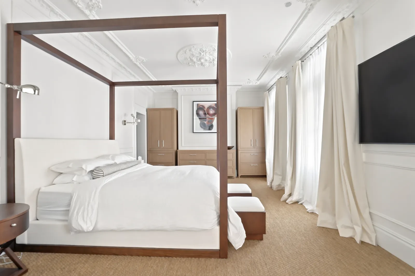 Main bedroom with a four-poster bed and full-length curtains layered over sheers