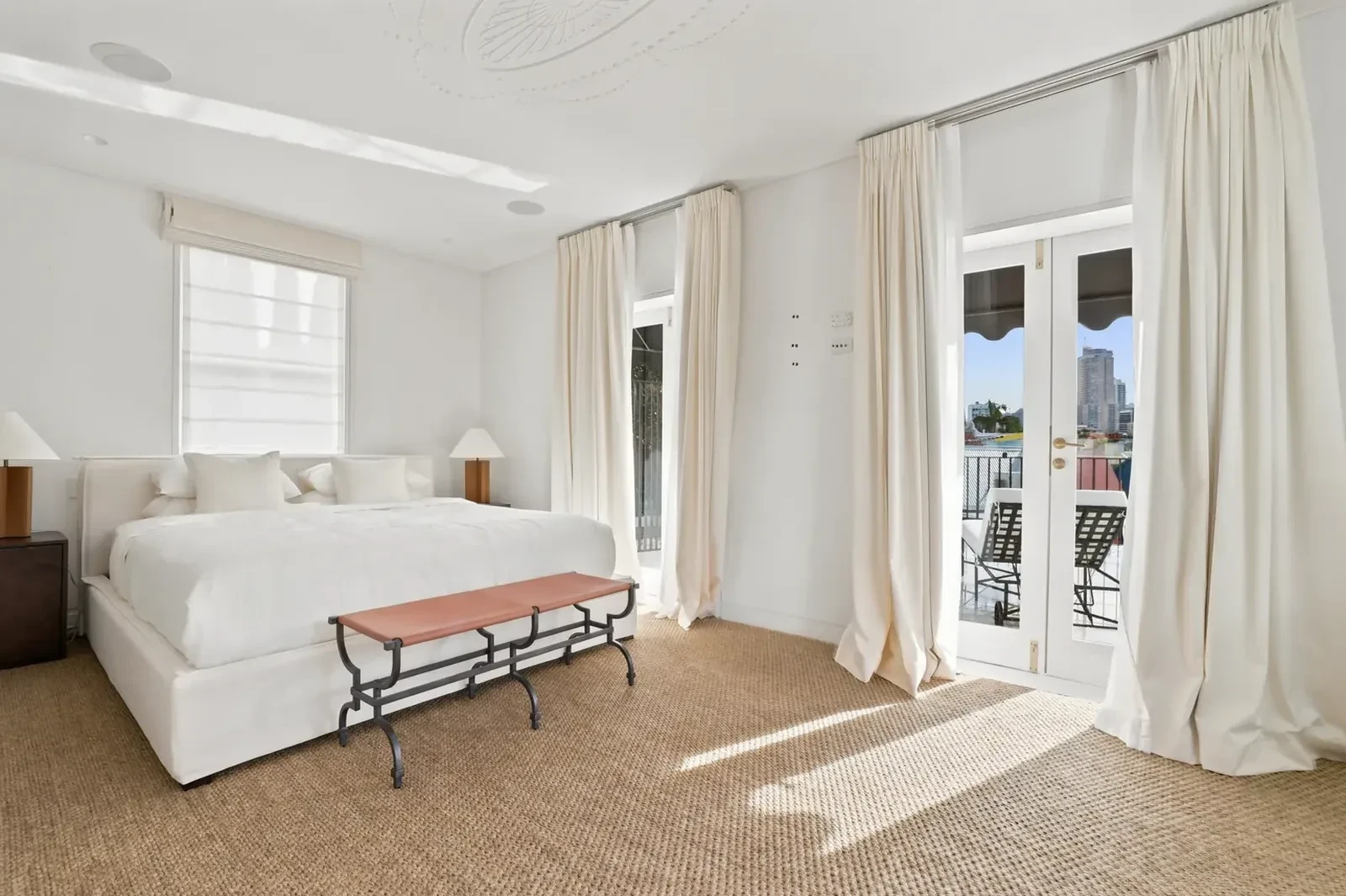 Guest bedroom with a roman blind over the window and layered curtains on the French doors
