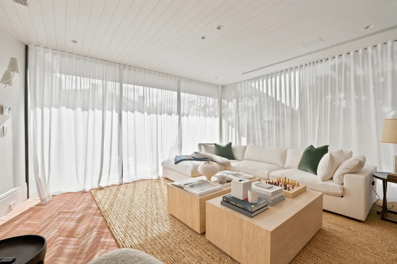 Living area in the rear extension with soft wave sheer curtains on ceiling track wrapping two walls of glass