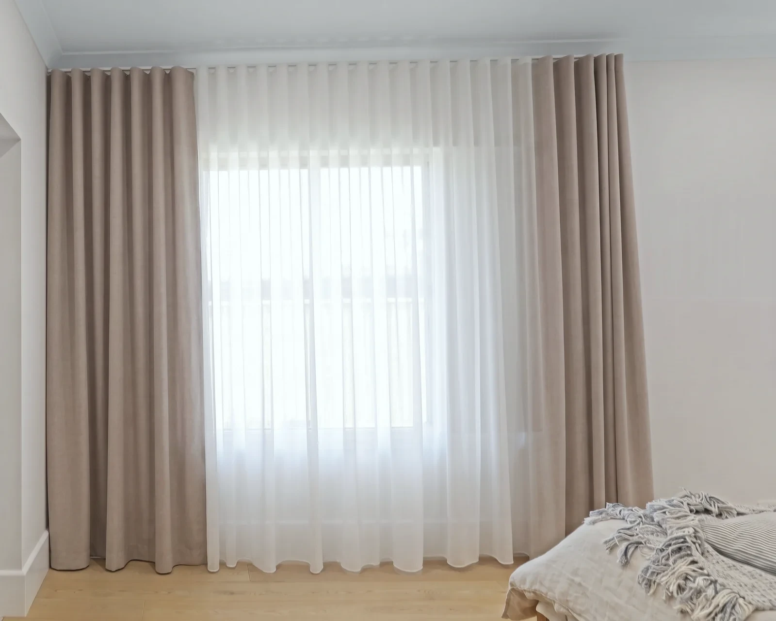 Double curtains on ceiling tracks: white sheer closed across the window, taupe blockout drawn open
