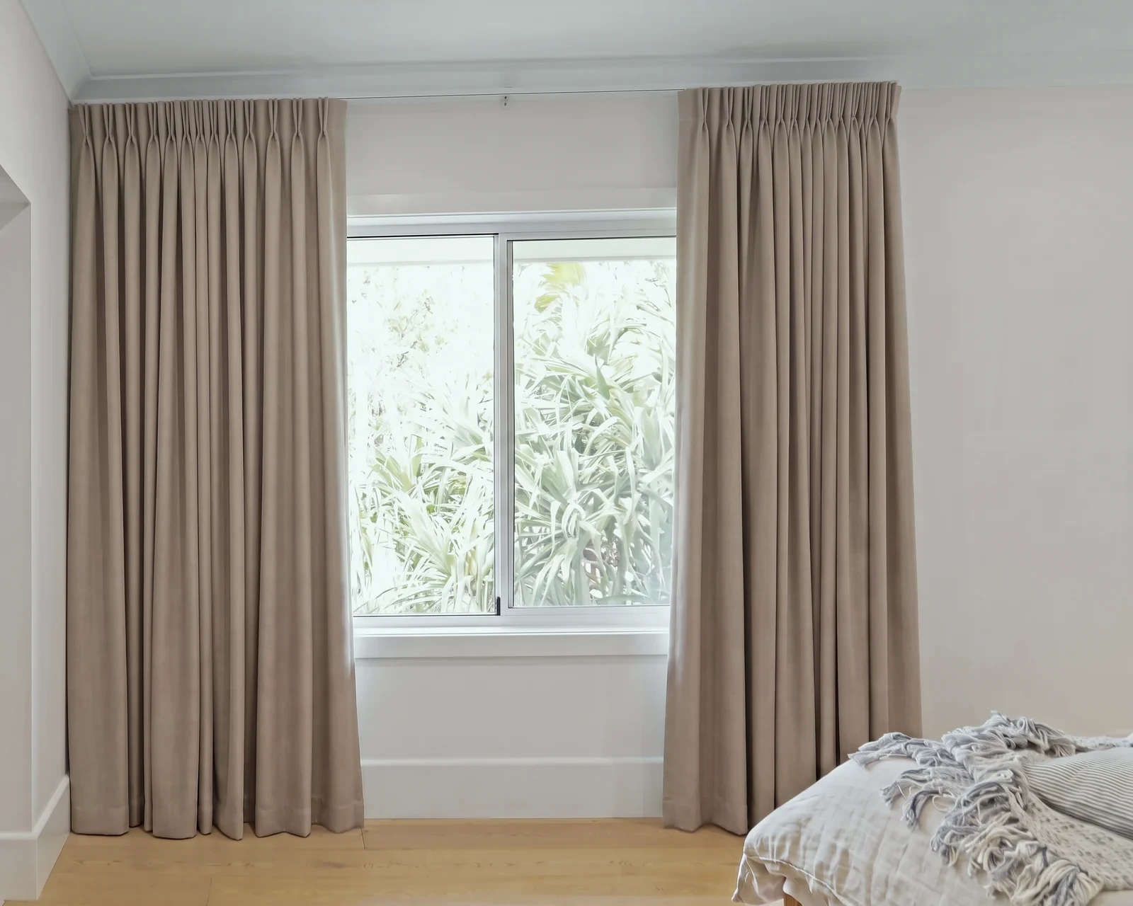 Taupe blockout pencil pleat curtains on a ceiling track, drawn open either side of a window