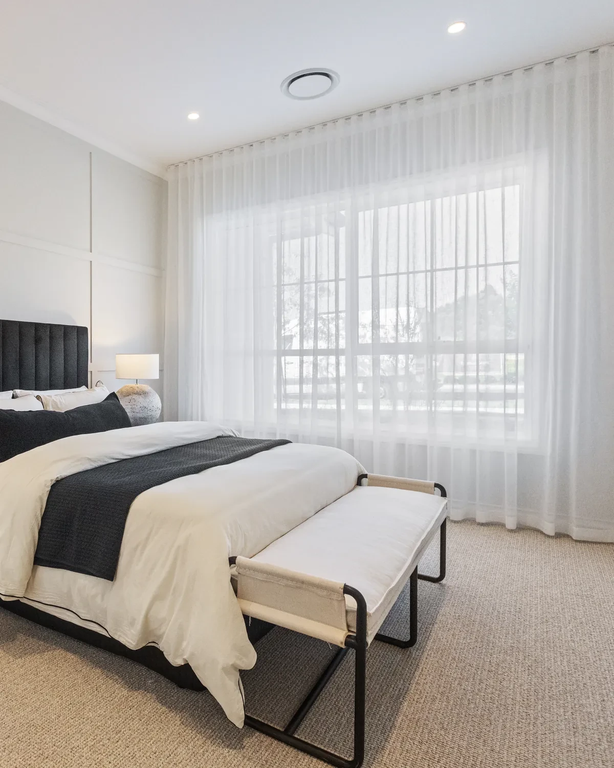 Guest bedroom in the Ashbourne display home with a wide Vevey Vanilla S-Fold sheer across the window wall