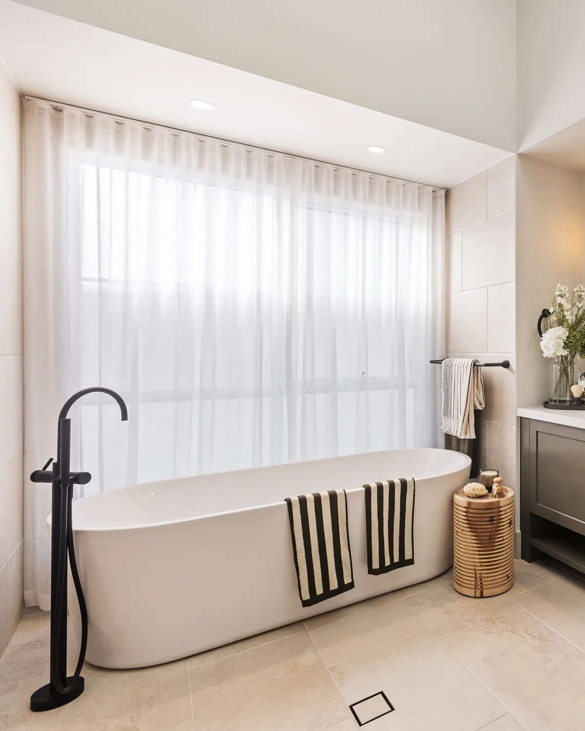 Ensuite in the Ashbourne display home: a freestanding bath under a window covered by a Vevey Vanilla S-Fold sheer
