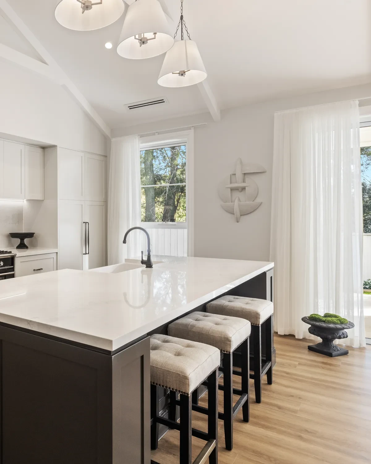 Kitchen in the Ashbourne display home with Vevey Vanilla sheer curtains on a window and a door beside the island bench