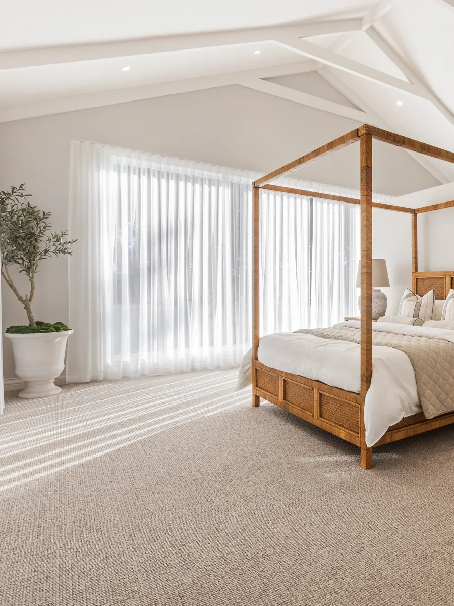 Main bedroom in Better Built Homes' Ashbourne display home: Vevey Vanilla S-Fold sheers from the ceiling to the floor behind a timber four-poster bed