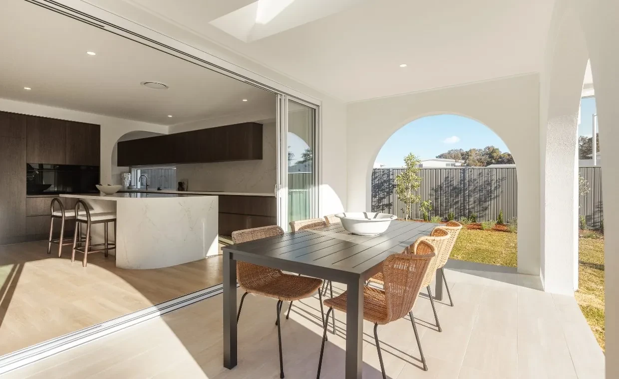 Outdoor dining in the Mariote 39 display home, with sliding doors open to the kitchen