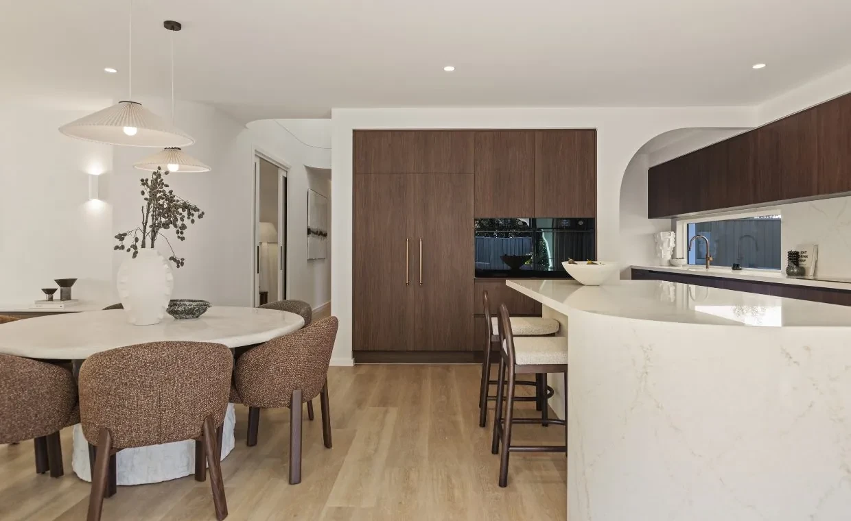 Kitchen and dining area in the Mariote 39 display home with a curved stone island and dark timber joinery