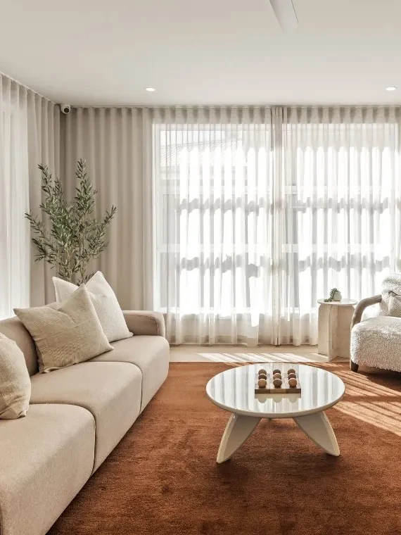Living room in Better Built Homes' Mariote 39 display home: S-Fold sheer curtains from the ceiling to the floor behind a cream sofa