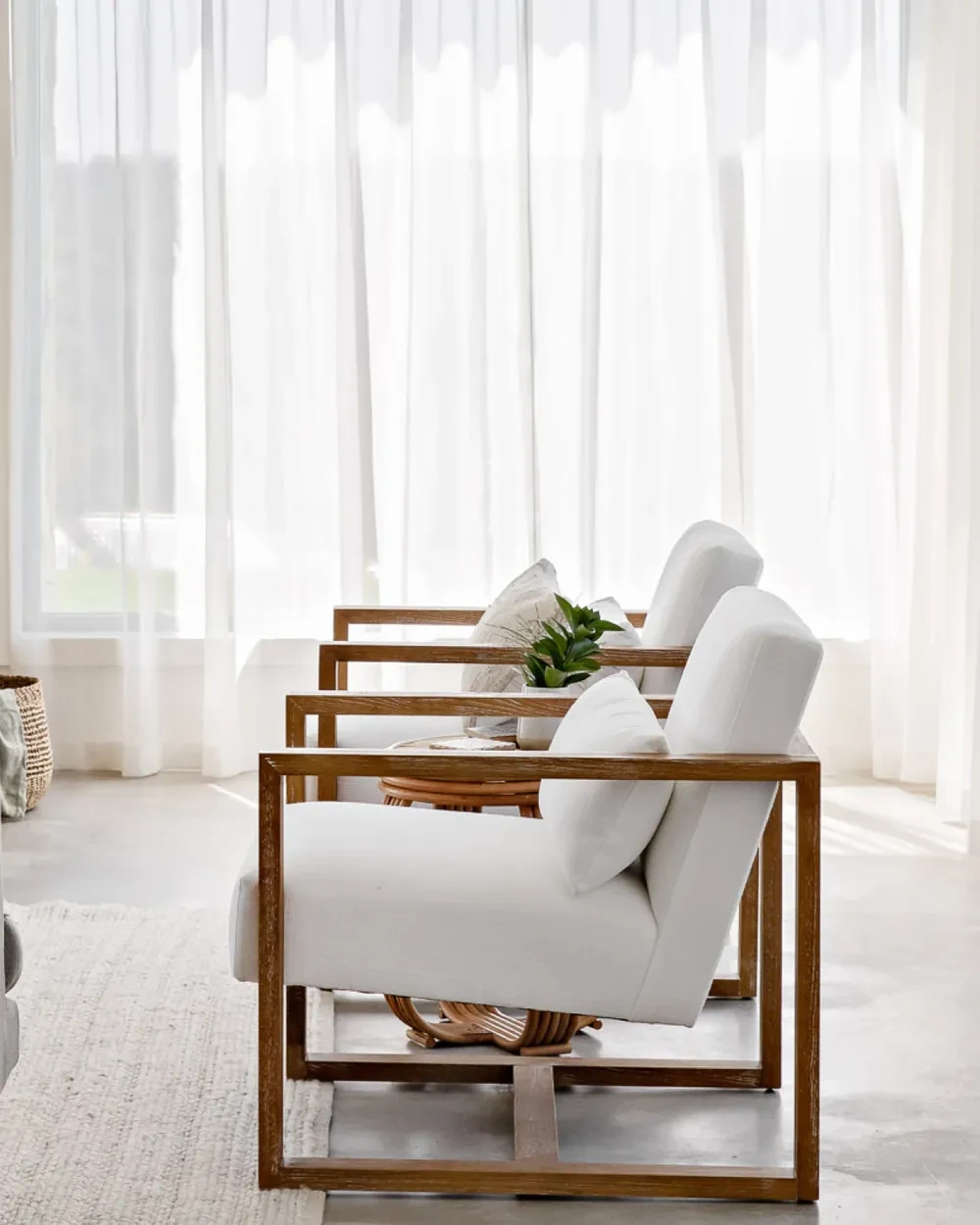 Ivory sheer curtains behind two armchairs in the Belmont Manor living room Ivory sheer curtains behind two armchairs in the Belmont Manor living room