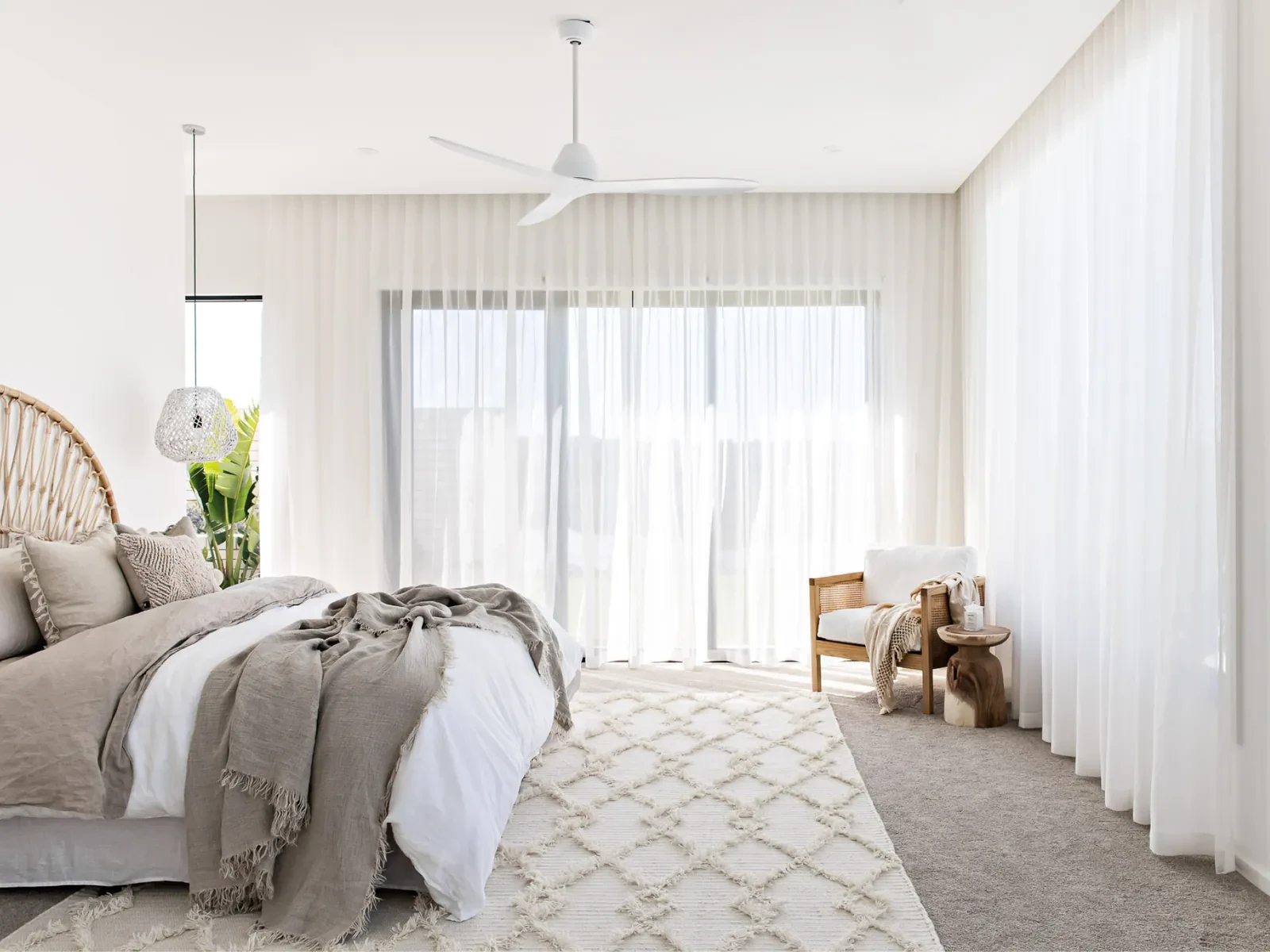 A main bedroom with ivory sheer curtains from the ceiling to the floor along two walls of windows and doors A main bedroom with ivory sheer curtains from the ceiling to the floor along two walls of windows and doors