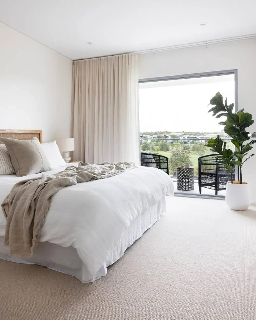 A bedroom with a sand-coloured curtain from the ceiling to the floor beside a sliding door that opens onto a balcony A bedroom with a sand-coloured curtain from the ceiling to the floor beside a sliding door that opens onto a balcony